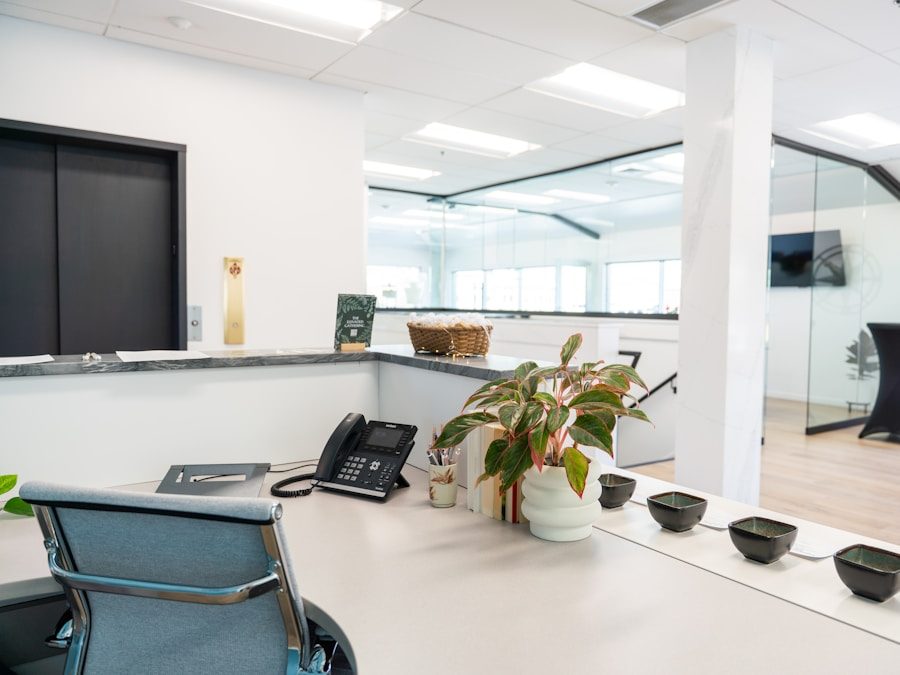 A small office reception desk with a phone, notepad and potted plant